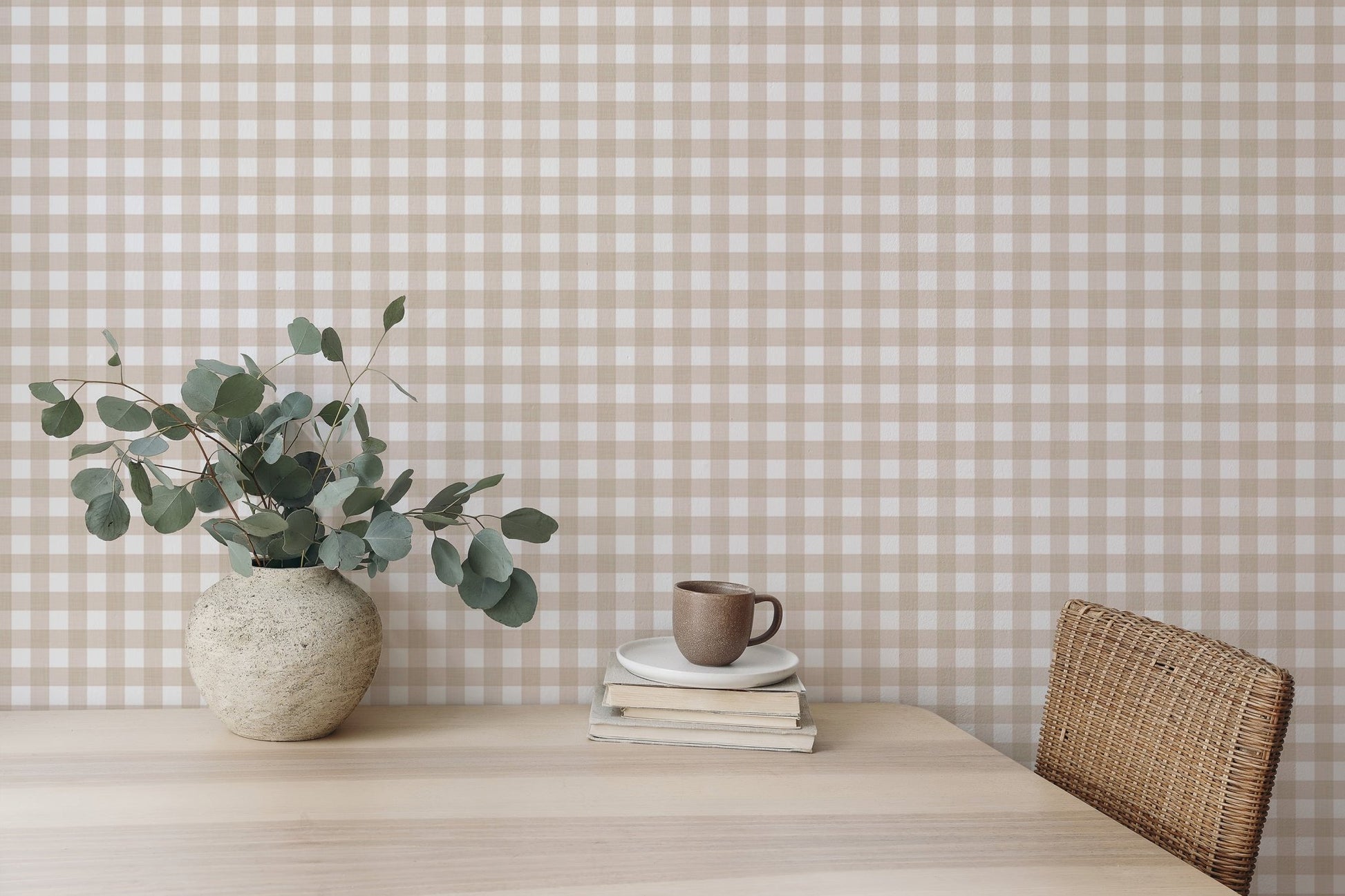 Wooden desk with a vase of leaves and beige checkered wallpaper background.