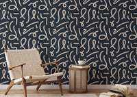 Abstract line wallpaper in a lounge area with a wicker chair and side table.