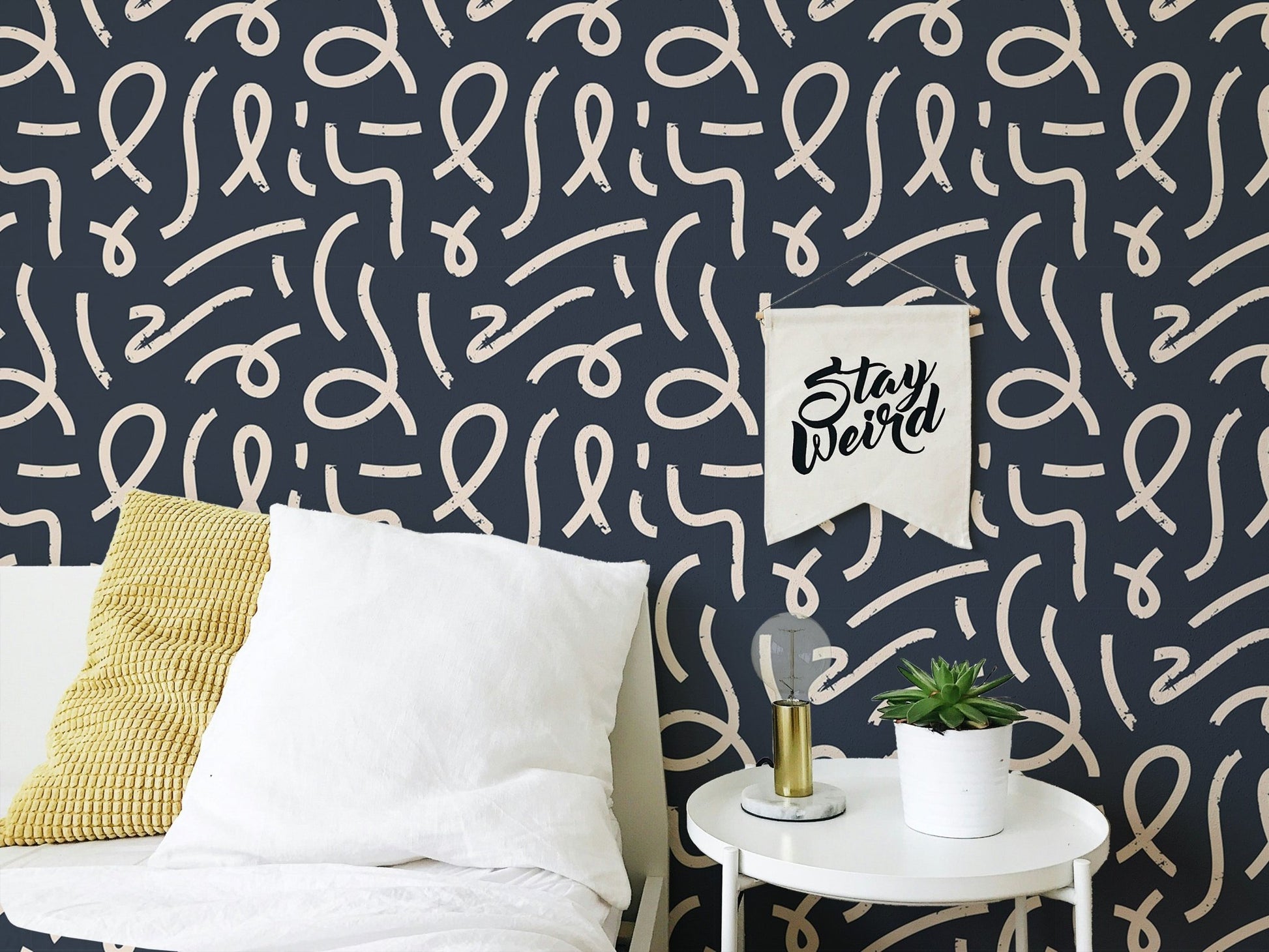 Patterned line wallpaper behind a bed with white and yellow pillows.
