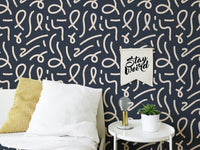Patterned line wallpaper behind a bed with white and yellow pillows.