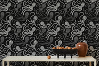 Black and white wallpaper with abstract octopus design behind dining table.