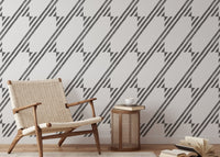 Minimalist chair next to a black and white diagonal stripe wallpaper feature wall.