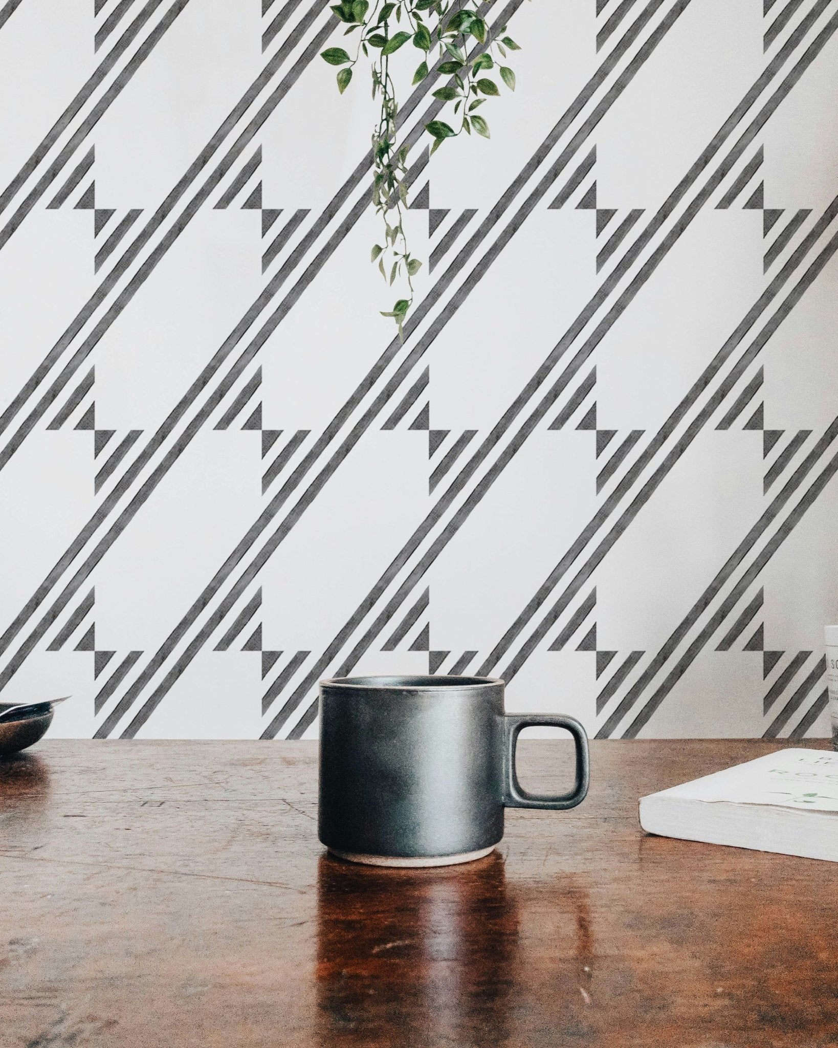 Coffee mug on a table in front of a black and white diagonal stripe wallpaper