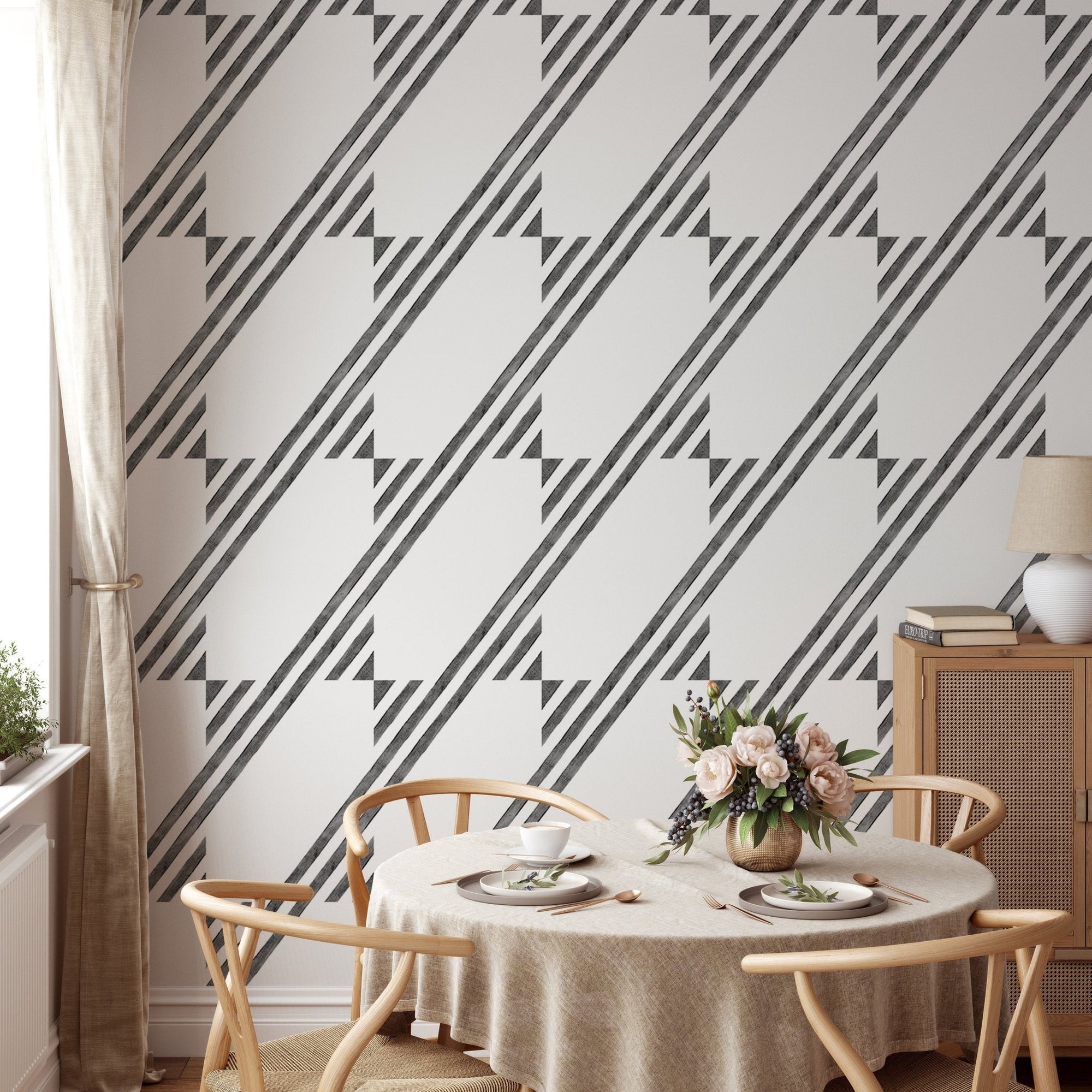 Dining room with black and white diagonal stripe wallpaper and round wooden table.