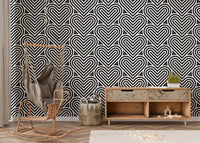 Linear heart wallpaper in a nursery area with a hanging chair and wood chest.