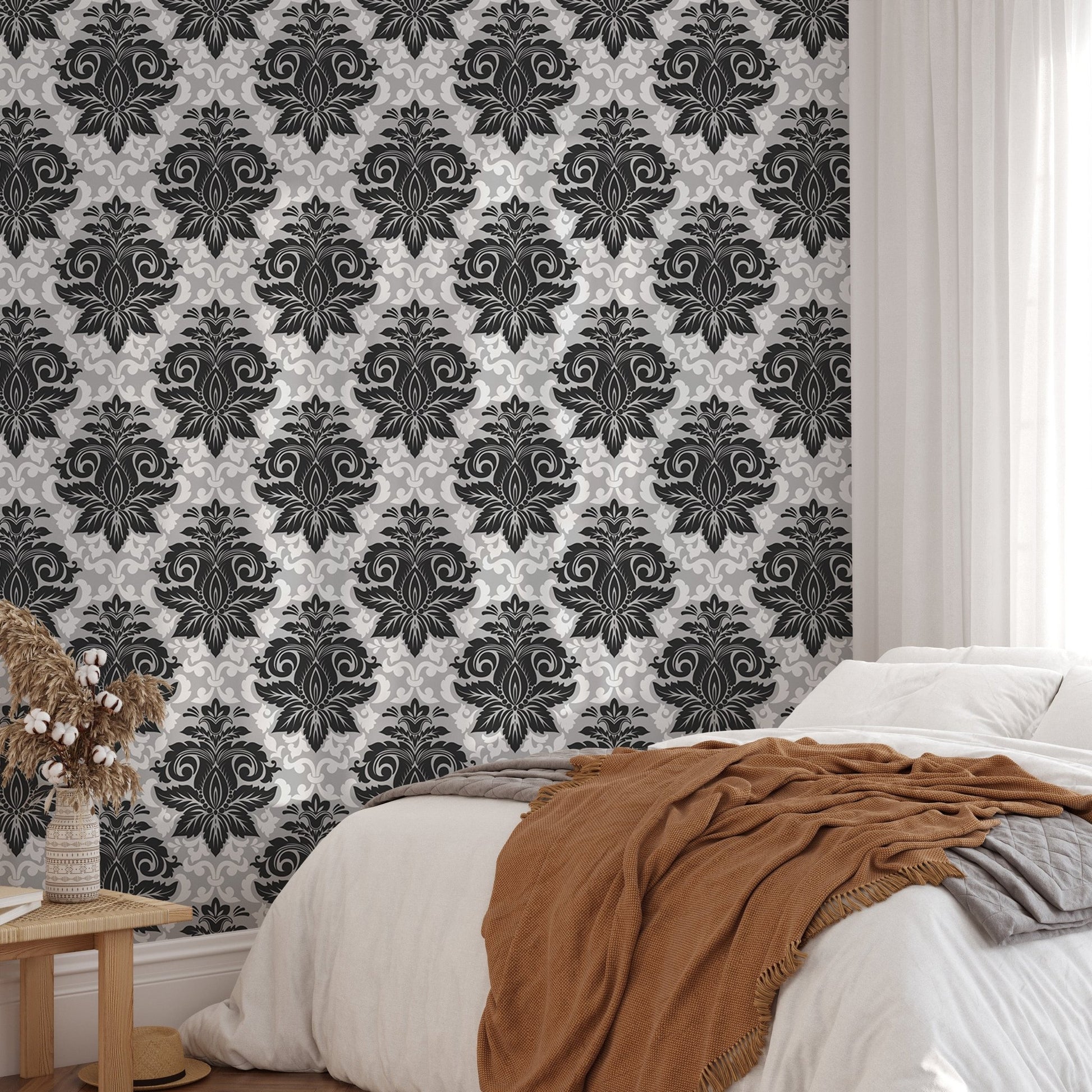 Ornate damask pattern wallpaper behind a bed with a brown throw blanket in bedroom