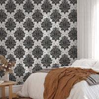 Ornate damask pattern wallpaper behind a bed with a brown throw blanket in bedroom