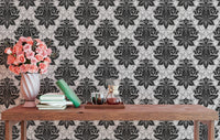 Black and white damask wallpaper on a living room wall with a wooden table.