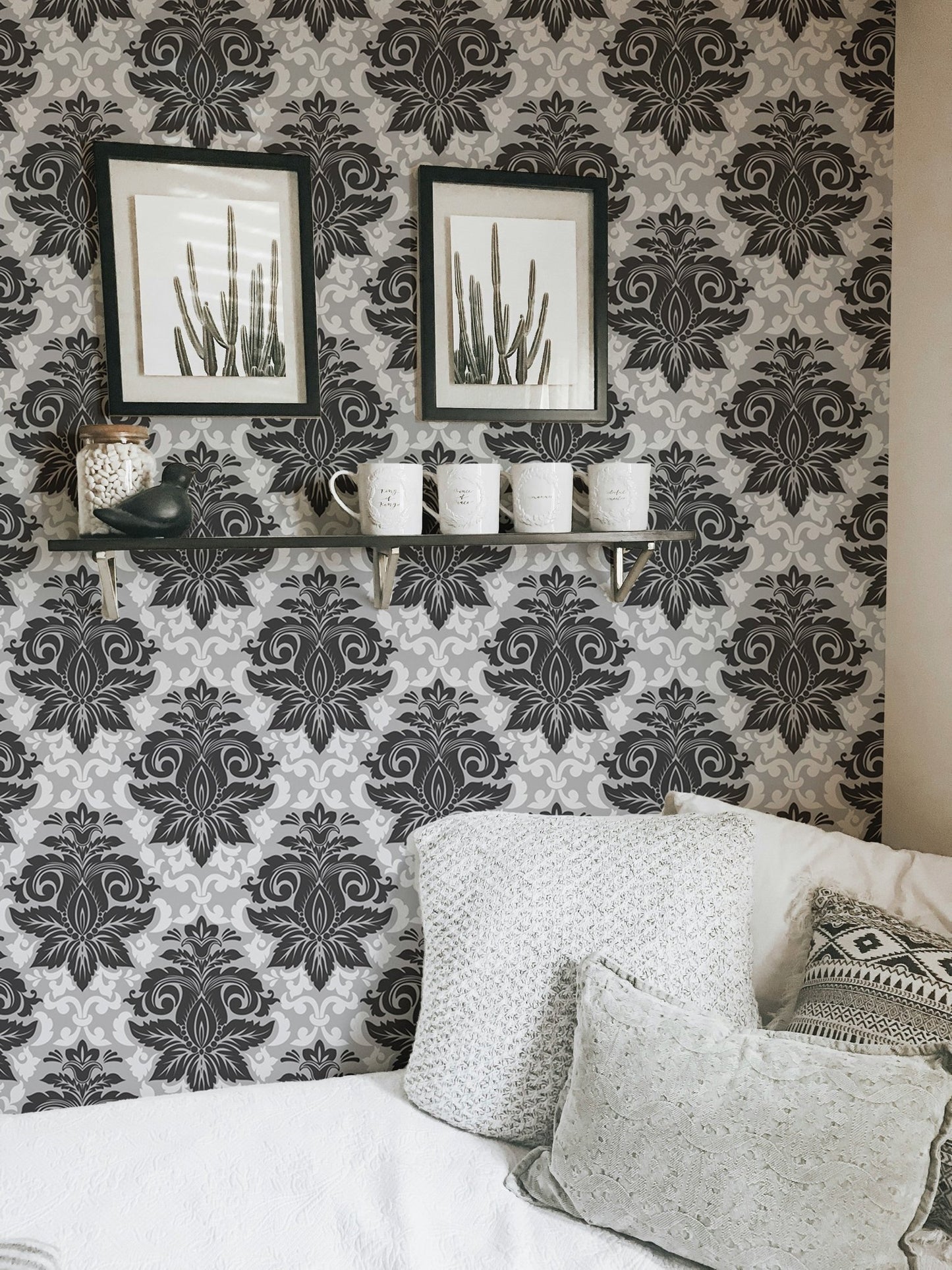 Greyish damask wallpaper decorated with framed art in a living room corner.