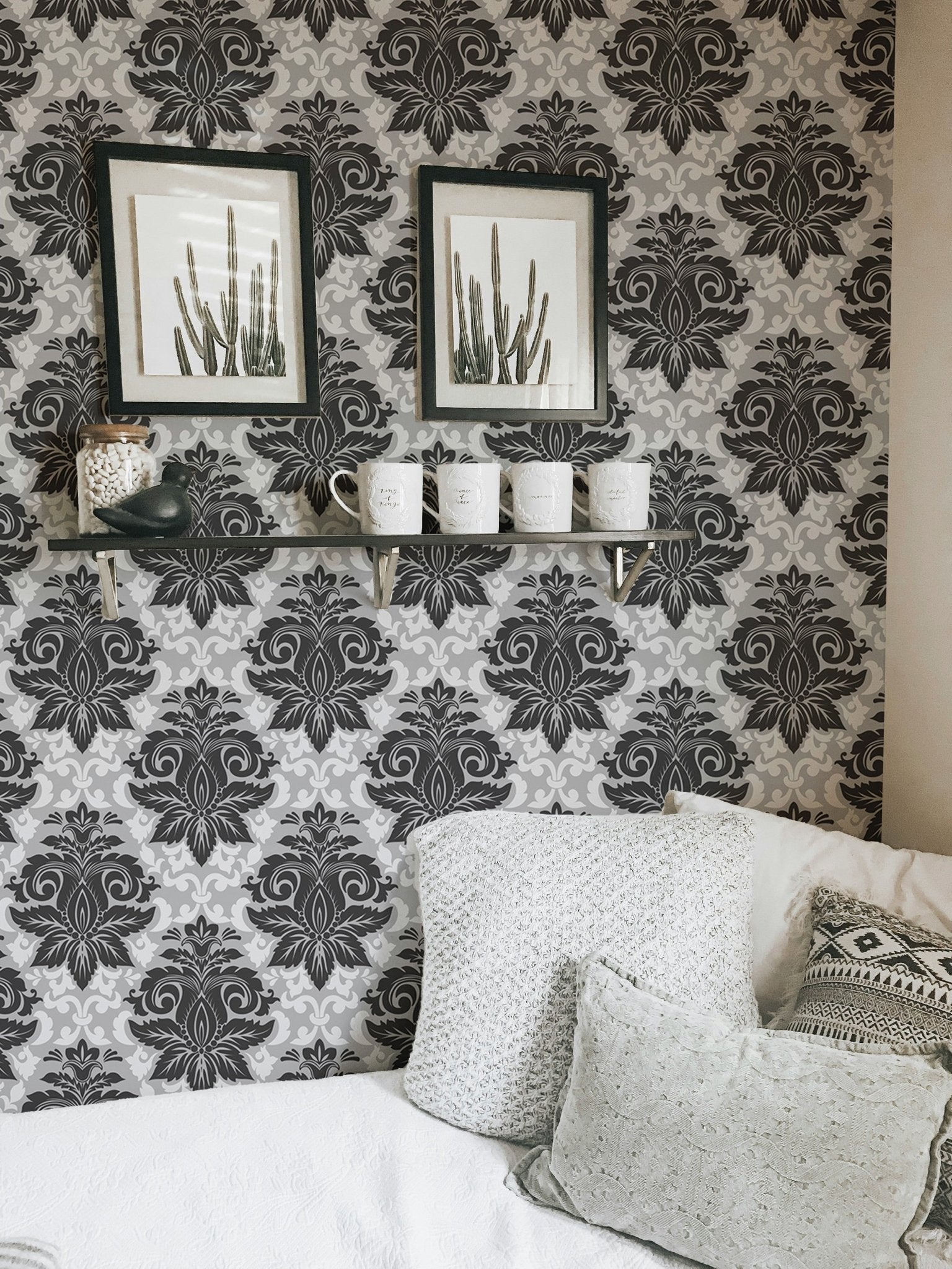 Greyish damask wallpaper decorated with framed art in a living room corner.
