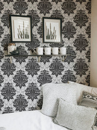 Greyish damask wallpaper decorated with framed art in a living room corner.