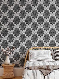 Intricate damask wallpaper in a bedroom featuring a wooden side table and vase.