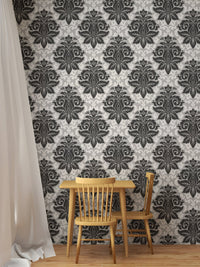 Greyish damask wallpaper behind a small wooden dining set and white curtain.