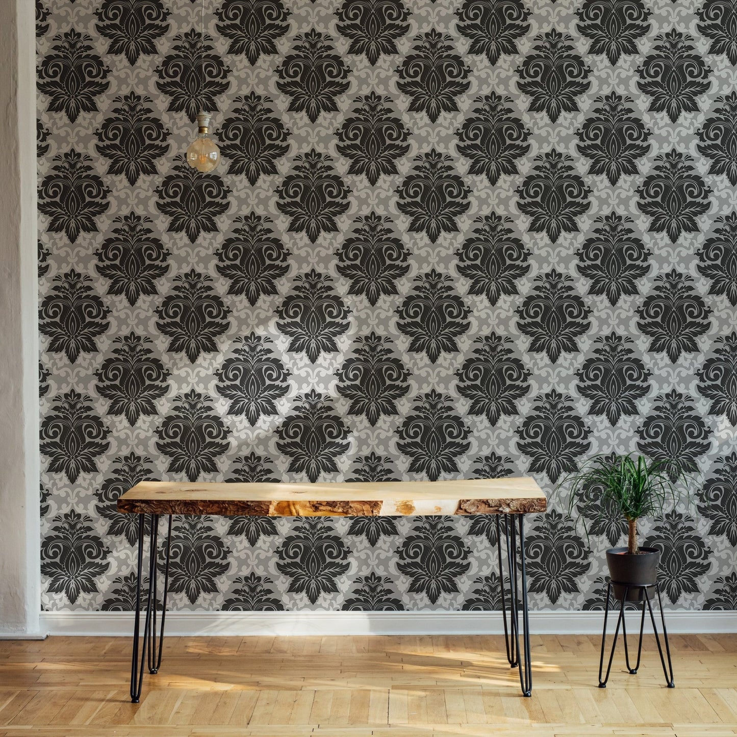 Large scale damask wallpaper behind a slim wooden console table in a hallway.