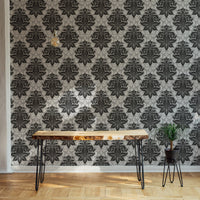 Large scale damask wallpaper behind a slim wooden console table in a hallway.
