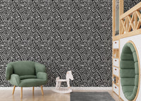 Monochrome ancient geometric wallpaper in a nursery with a green armchair.