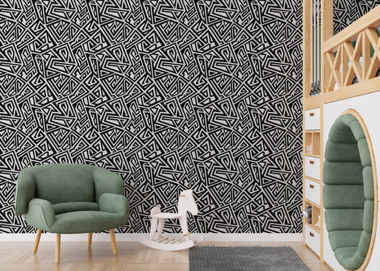 Monochrome ancient geometric wallpaper in a nursery with a green armchair.