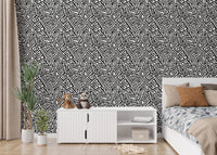 Bedroom wallpaper with geometric patterns next to a white dresser and plants.