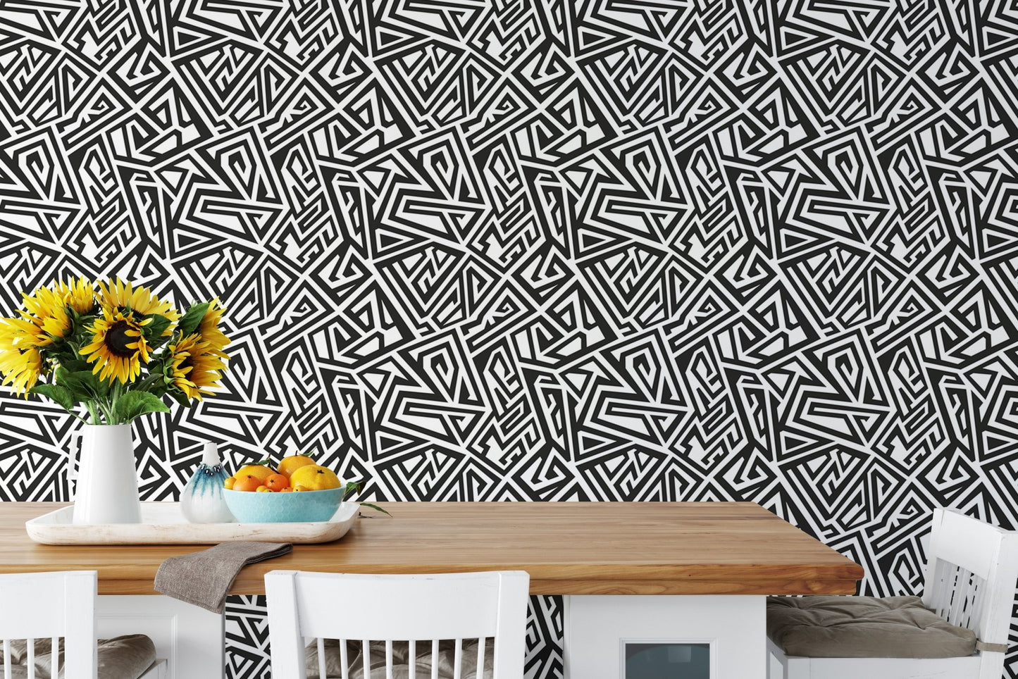 Black and white geometric wallpaper behind a wooden dining table and chairs.