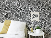 Modern bedroom with black and white ancient geometric wallpaper and white bedding.