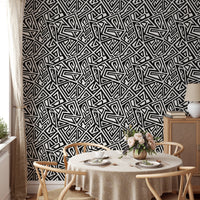 Dining area featuring monochrome geometric wallpaper and a round table.