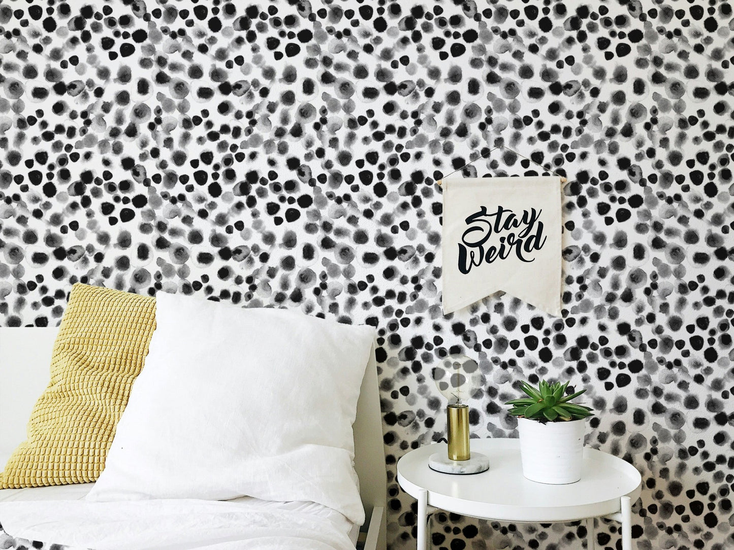 Black and white patterned wallpaper behind a bed with yellow accent pillows.