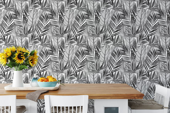 Tropical palm leaves wallpaper behind dining table with sunflowers and fruit.