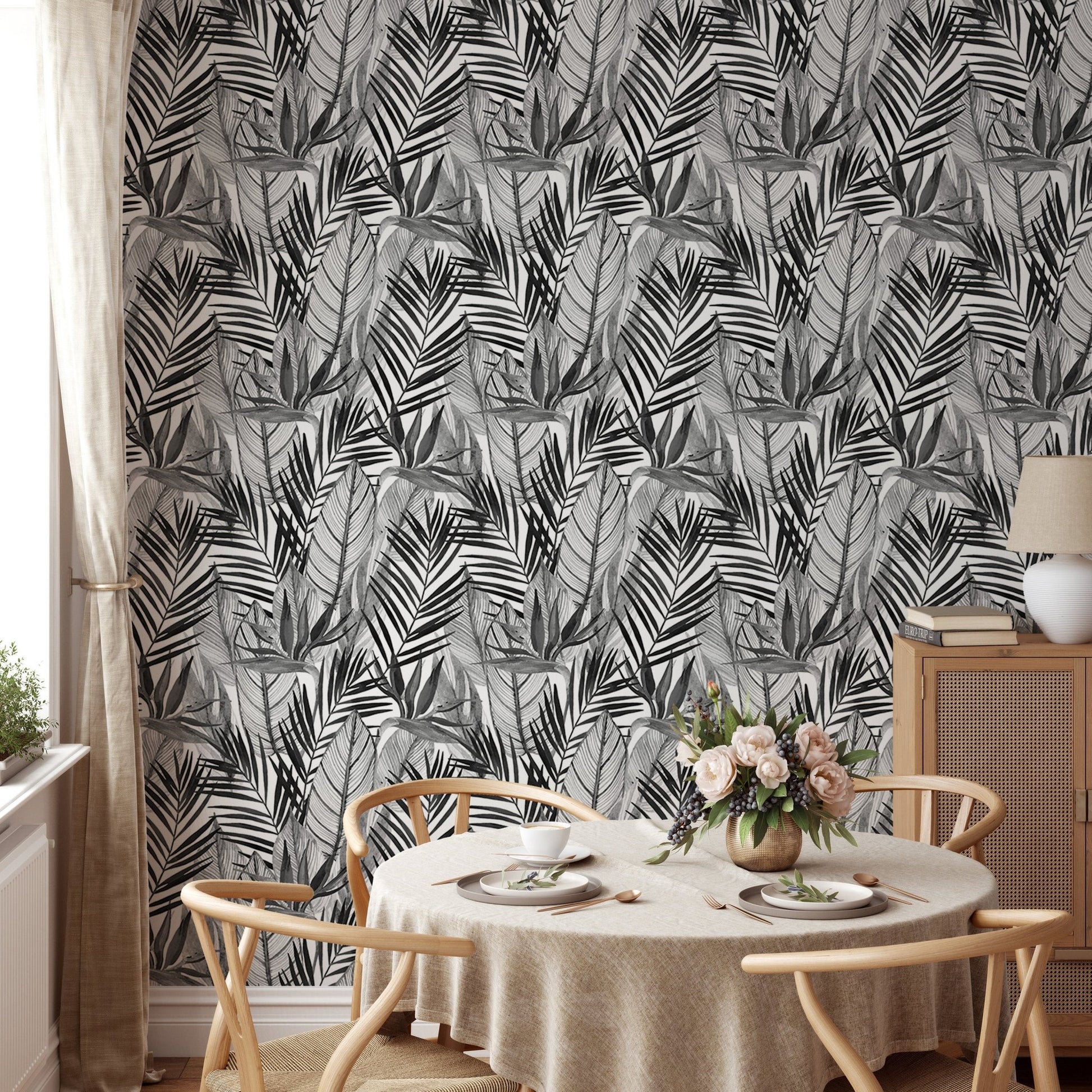 Black and white palm leaves wallpaper in dining room with round table.