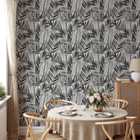 Black and white palm leaves wallpaper in dining room with round table.