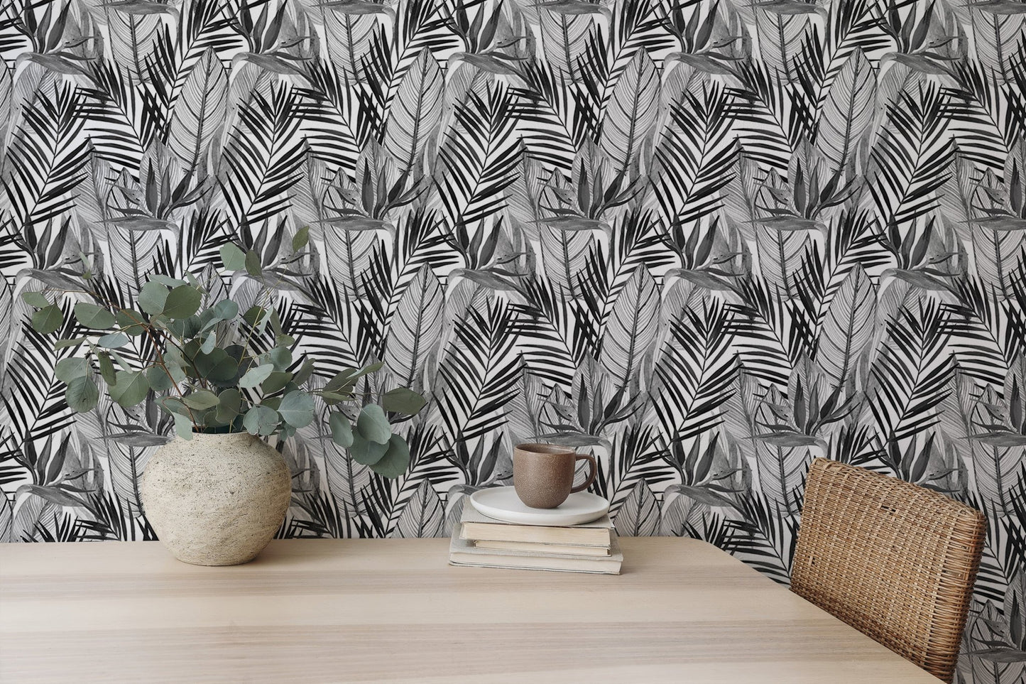 Tropical palm leaves wallpaper behind home office desk with potted plant.