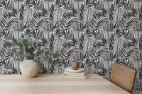 Tropical palm leaves wallpaper behind home office desk with potted plant.