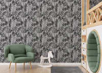 Palm leaf wallpaper in kids playroom with green armchair and white toys.