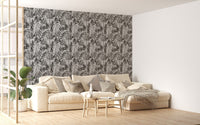 Black and white watercolor wallpaper in living area with beige sofa and plants.
