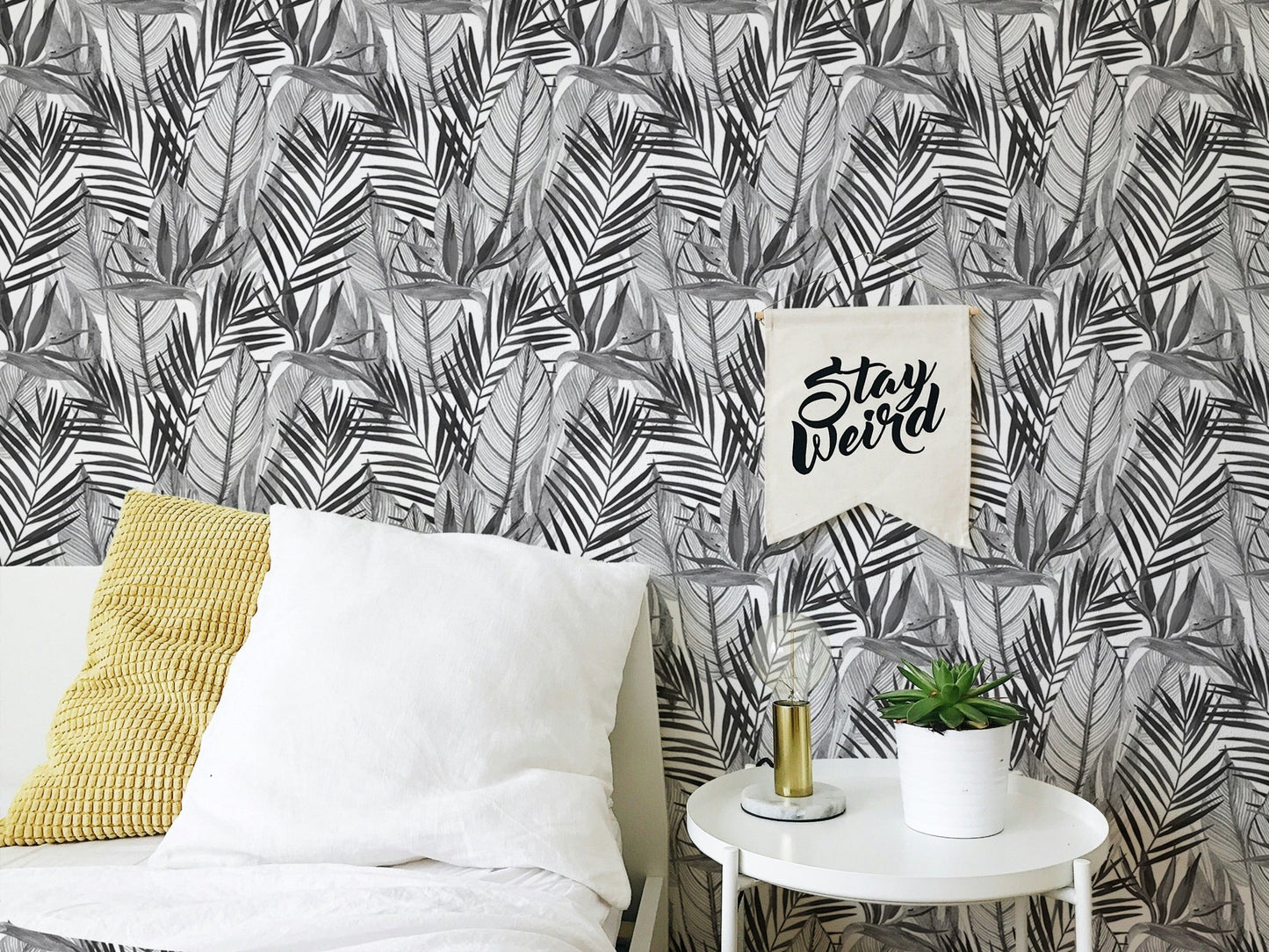 Tropical wallpaper in bedroom with white bedding and yellow cushion.