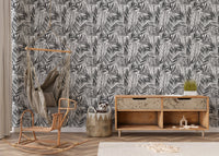 Botanical palm leaf wallpaper behind wooden sideboard and rattan chair.