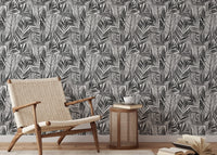 Black and white botanical wallpaper behind light wood chair and side table.
