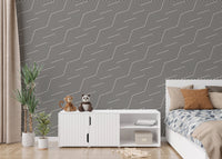 Modern black and white geometric wallpaper in a child's bedroom with white furniture.