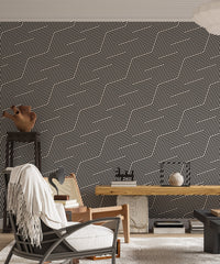 Geometric wallpaper behind a wooden desk and white armchair in a study room.