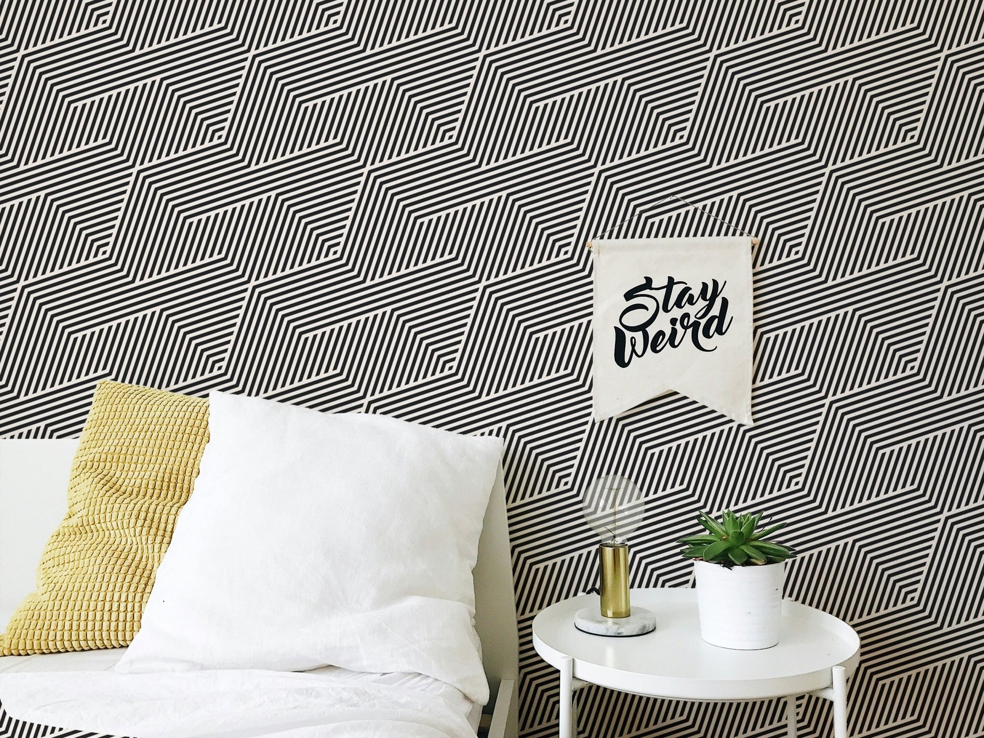 Monochrome zigzag wallpaper behind a white bed with yellow pillows.