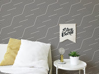 Monochrome zigzag wallpaper behind a white bed with yellow pillows.