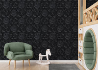Black abstract damask wallpaper in a nursery with a green armchair and toy horse.