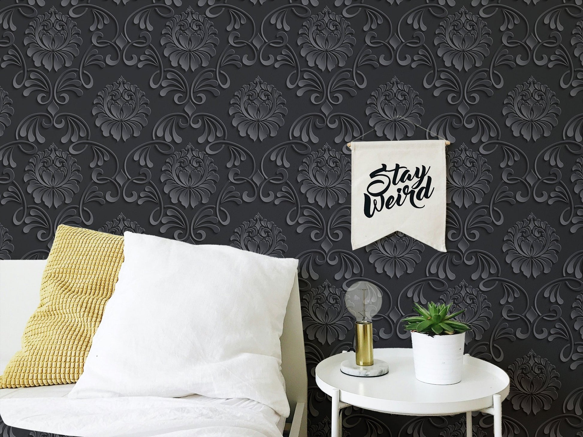 Dark damask wallpaper in a relaxation corner with a white pillow and side table.
