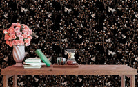 Study area wall decorated with black bird and branch wallpaper and a wooden table.