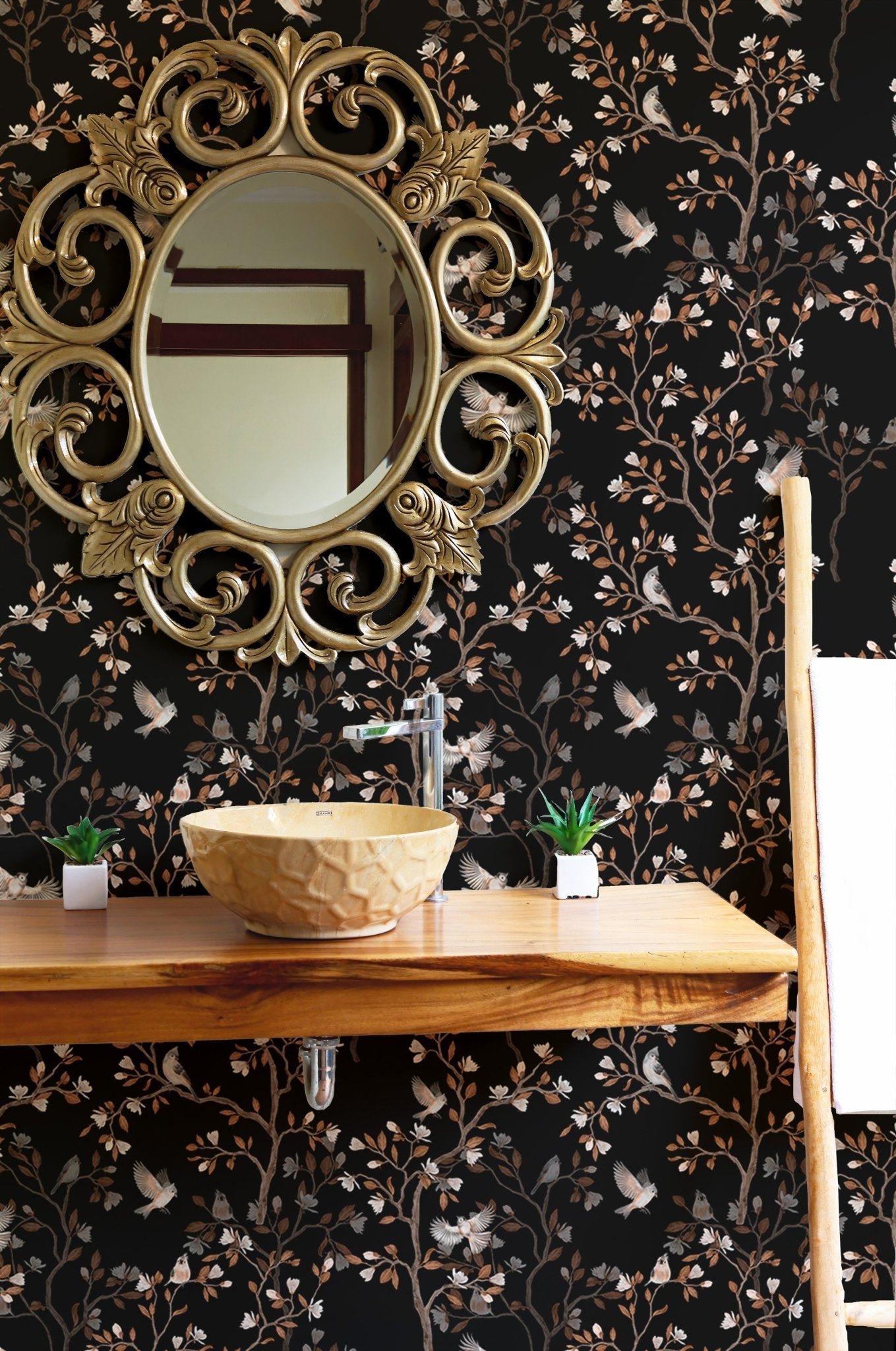 Bathroom wallpaper with black chinoiserie patterns behind a gold mirror and vanity.