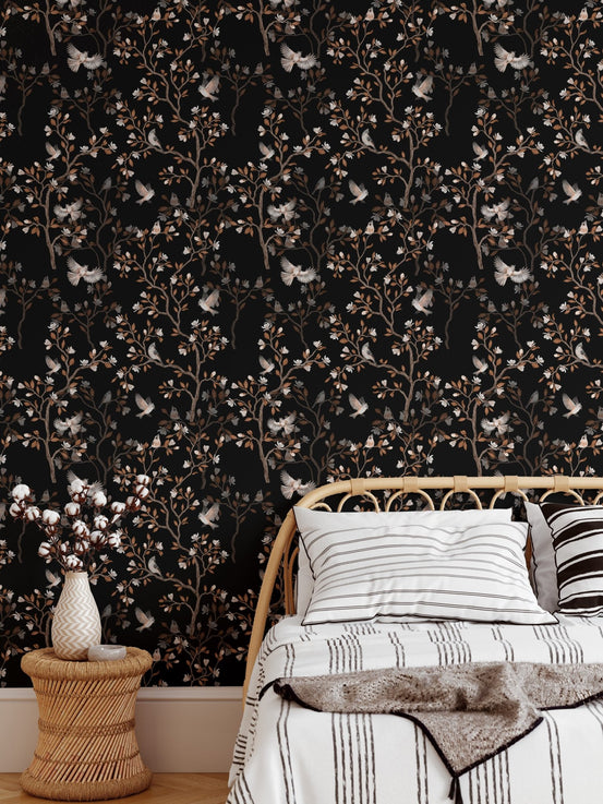 Bedroom wallpaper featuring dark floral patterns behind a white bed and side table.