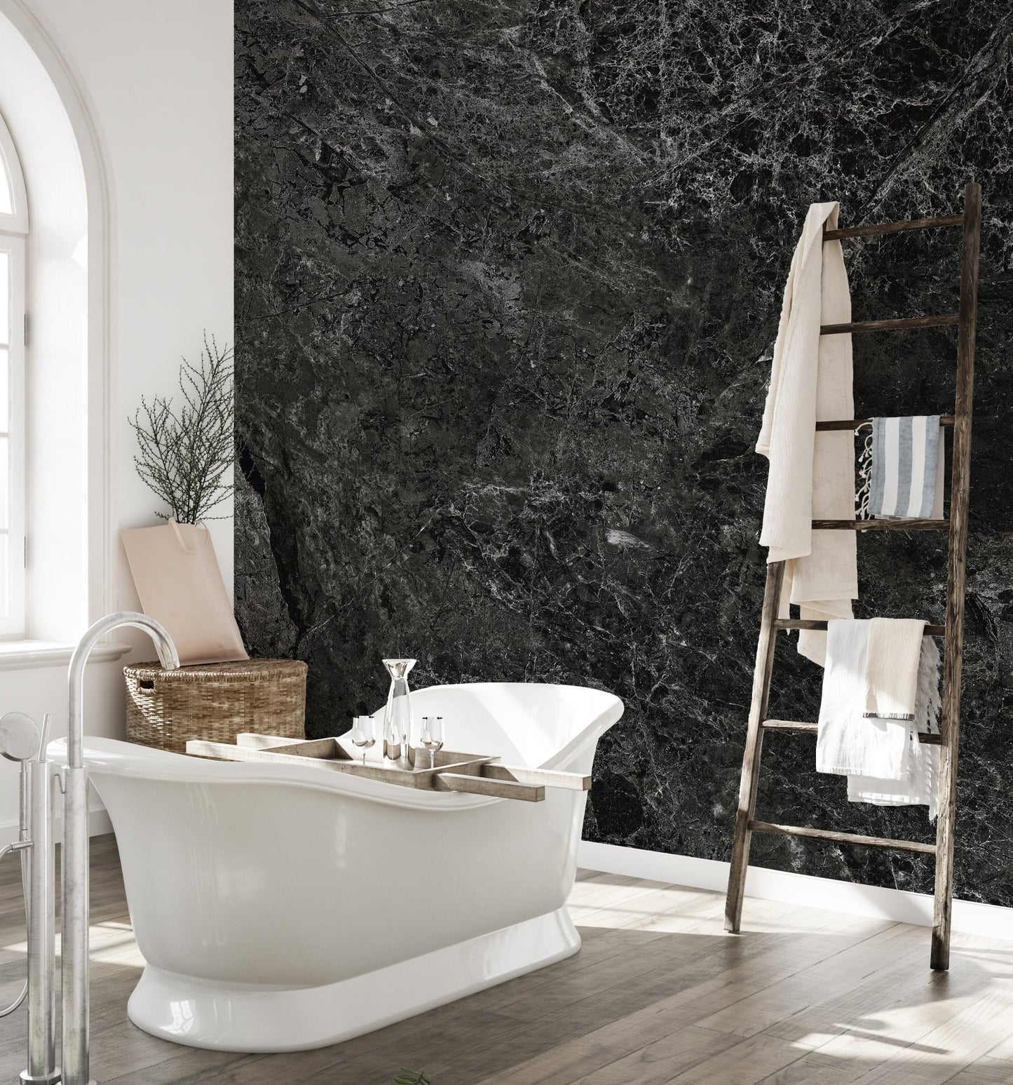 Dark stone wall mural behind a freestanding bathtub in a bright washroom.