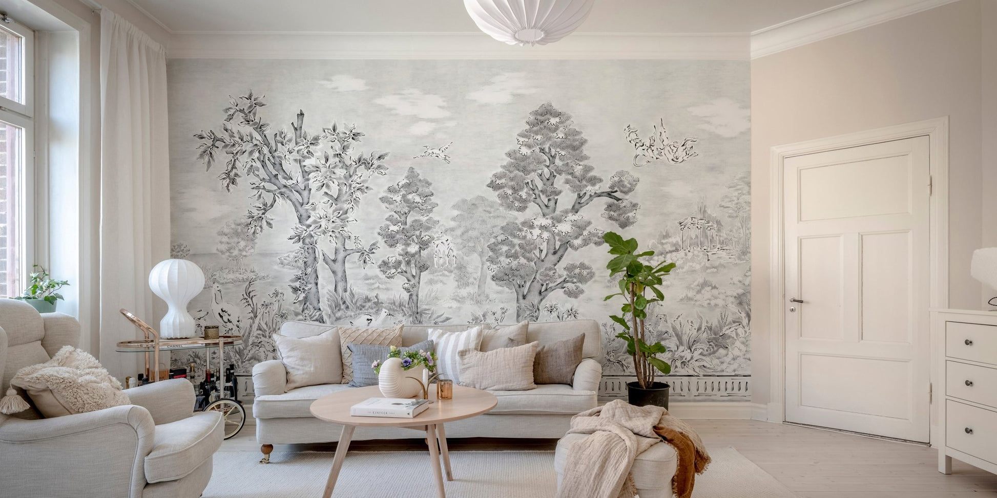 Monochrome tree wall mural behind a beige sofa in a contemporary living room.