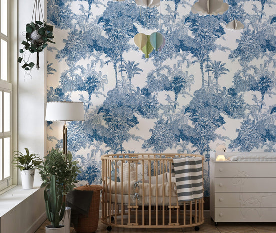 Blue and White Cobalt Tropical Palm Mountain Wallpaper in a nursery with a wooden crib.