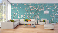 Open plan living area with teal flower wall mural and light wood flooring.