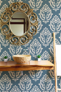 Textured blue pattern wallpaper in a bathroom with a round mirror.